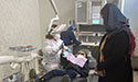 dental hygienist sits in clinic working on patient