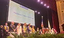 college faculty, staff and students standing on stage during an event